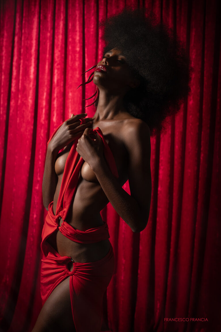 Modella nera su sfondo rosso illuminata dal fotografo di moda Francesco Francia